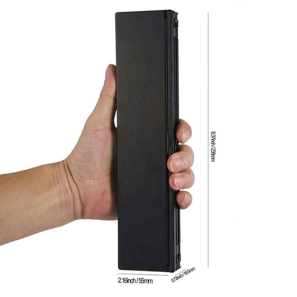Black folding Bluetooth keyboard with aluminium bottom next to tablet