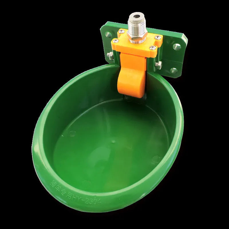 Green plastic automatic drinking bowl with nozzle for sheep and pigs on a farm.