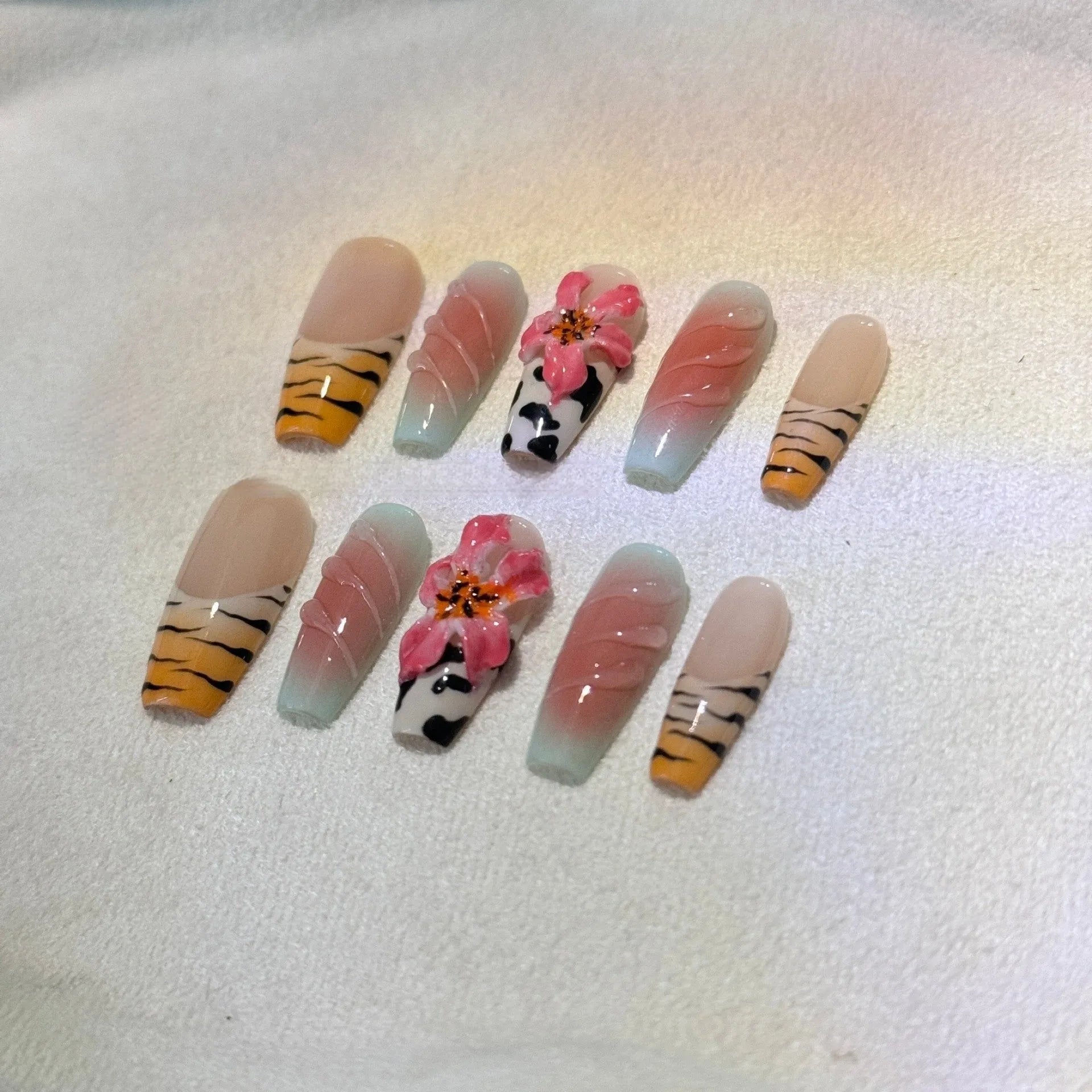 Zebra pattern and Lily hand carving design on a set of long, decorative false nails.