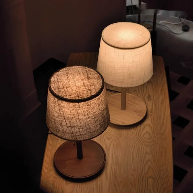 Walnut colour solid wood bedside lamp with a white fabric lampshade and a black cable switch.