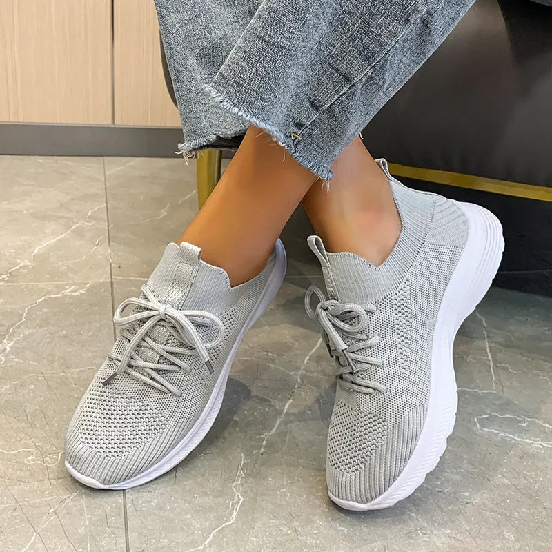 Women's Flyknit mesh running shoes in creamy white colour showing low-top slip-on design and rubber sole.