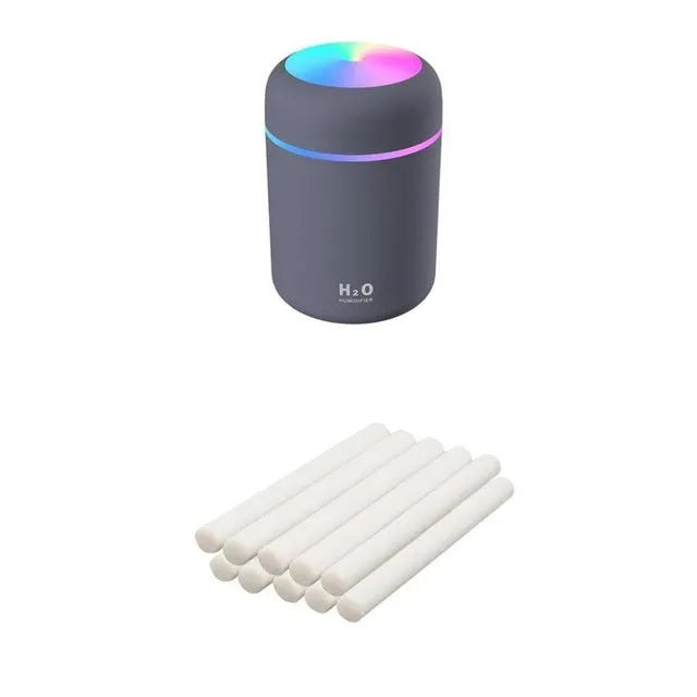 Pink USB desktop humidifier with LED lights next to a white mug on a desk