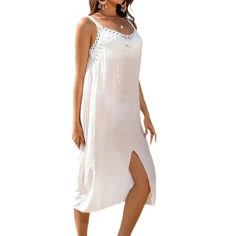 White women's crochet beach dress with suspenders and a bottom slit on a hanger.