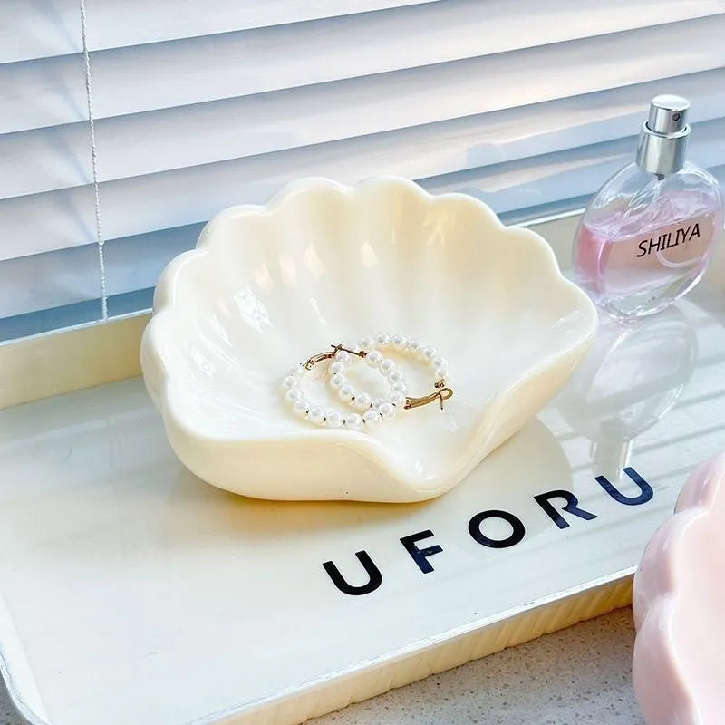 White plastic shell-shaped soap dish for bathroom countertop with soap bar on it.