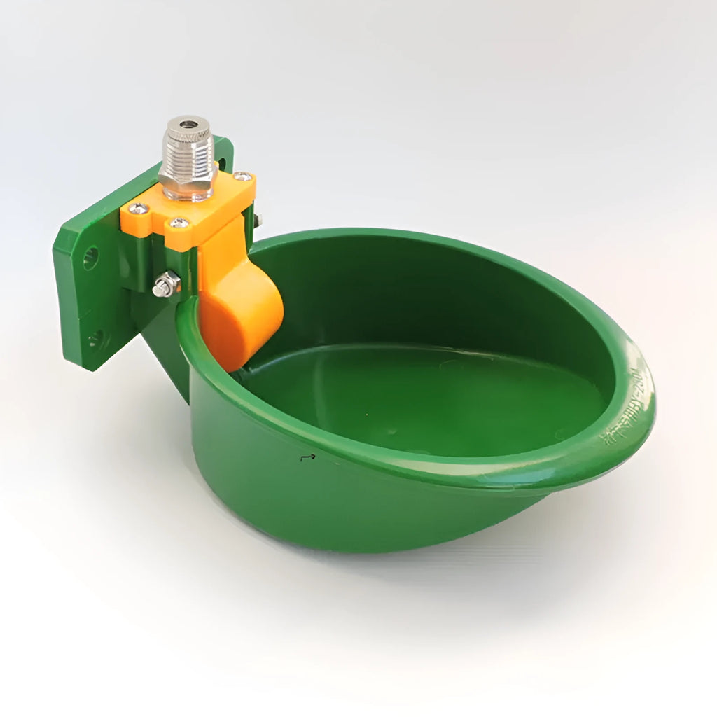 Green plastic automatic drinking bowl with nozzle for sheep and pigs on a farm.