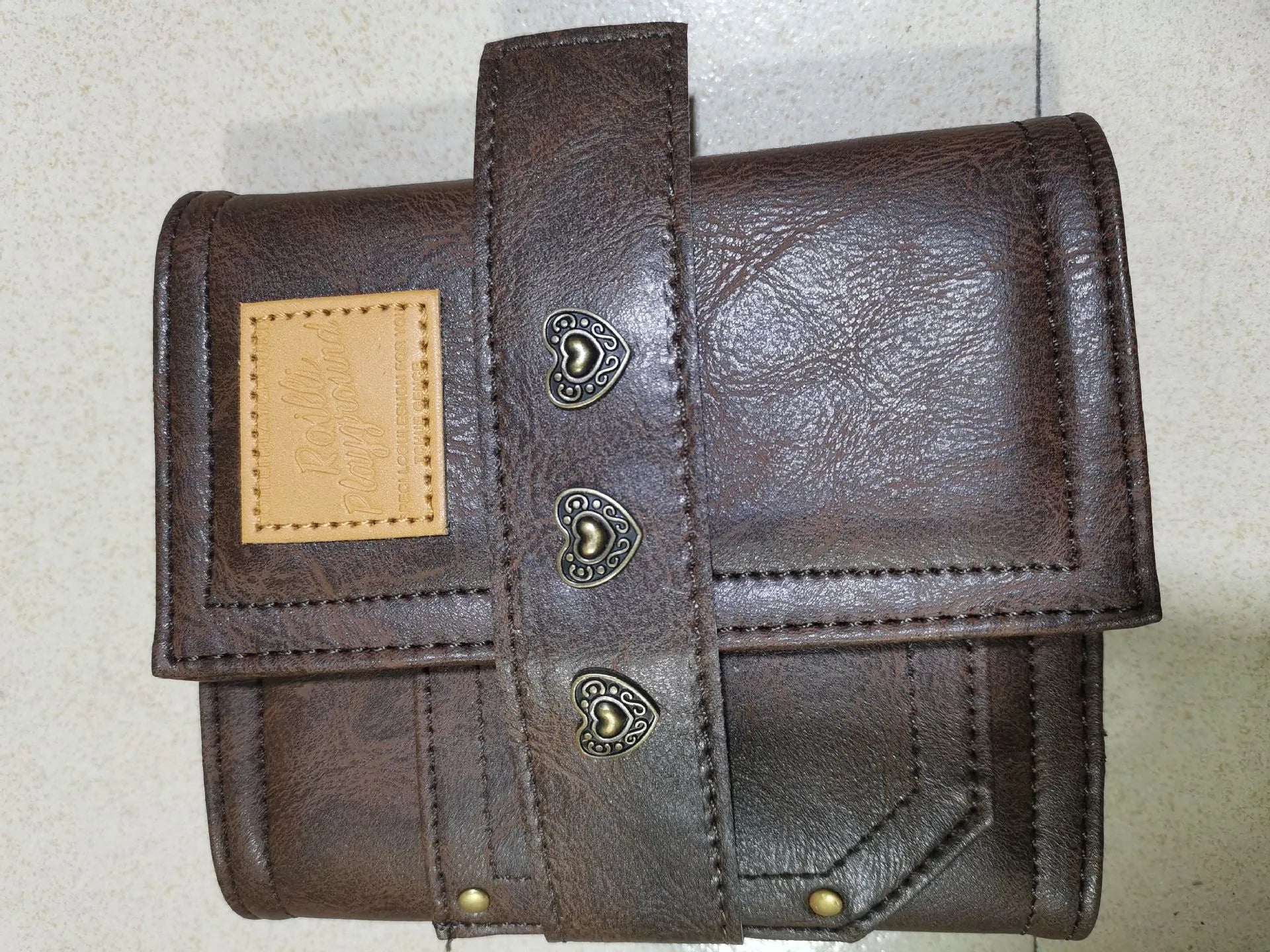 Brown A7 leather buckle notebook with loose-leaf binding on wooden surface
