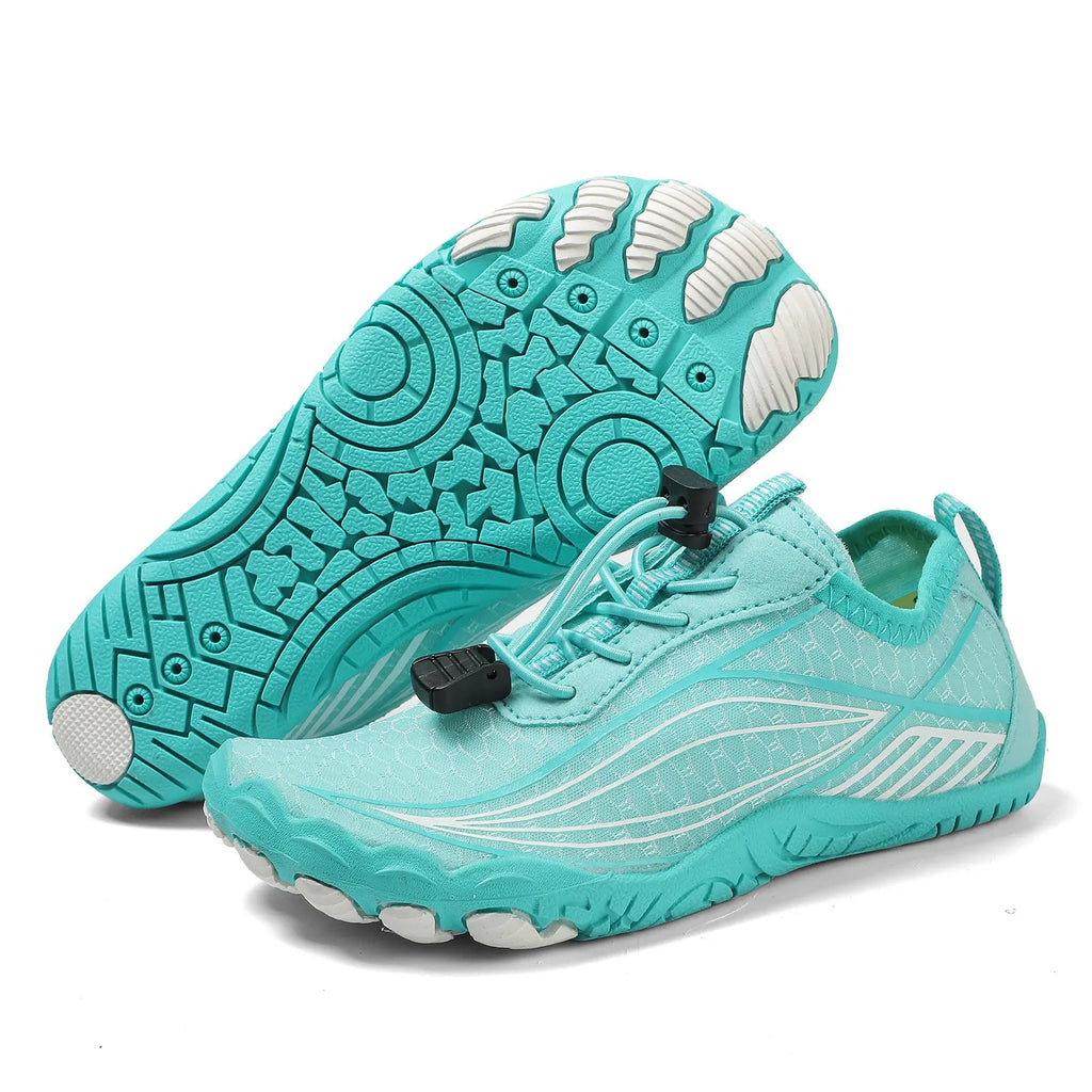 Children's elastic band wading shoes in grey with non-slip rubber sole, shown on a beach.