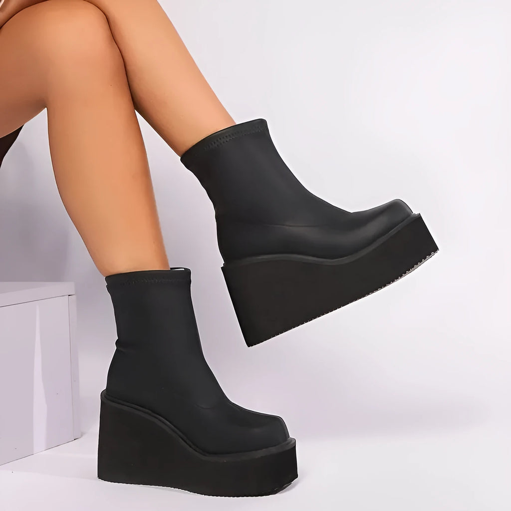 Plus size black artificial PU women's ankle boots with a wedge heel and round toe on a model.