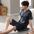 Man wearing a loose light blue short-sleeved ice silk pajama shirt and matching shorts.