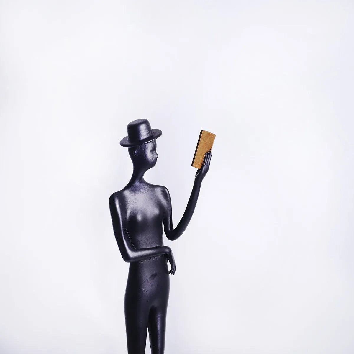 Black cast aluminium sculpture of a reading woman on a desktop, 51 cm tall.