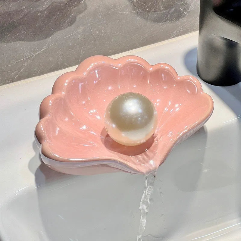 White plastic shell-shaped soap dish for bathroom countertop with soap bar on it.