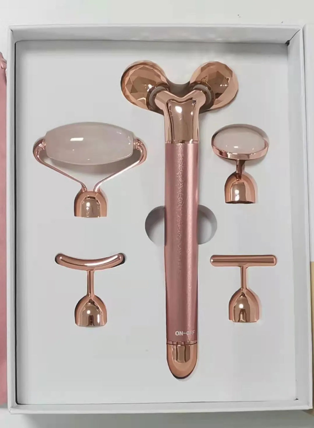 Rose gold five-in-one vibrating face lifting machine with four interchangeable jade and beauty heads in a compact box