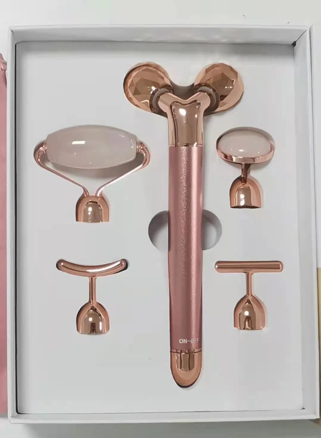 Rose gold five-in-one vibrating face lifting machine with four interchangeable jade and beauty heads in a compact box
