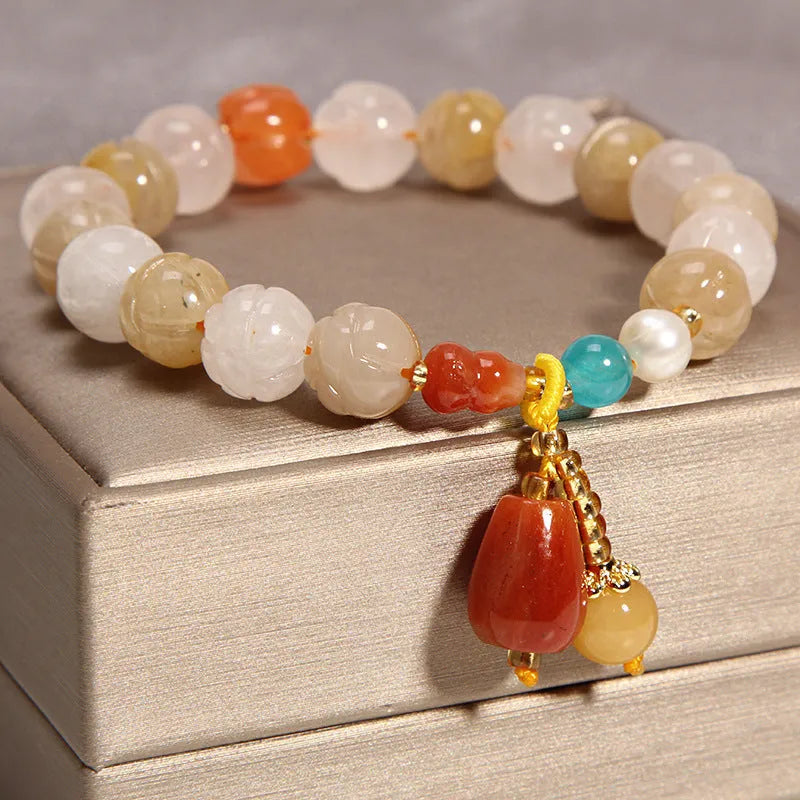 Khaki coloured crystal beads on a gold silk string bracelet, showing adjustable closure.