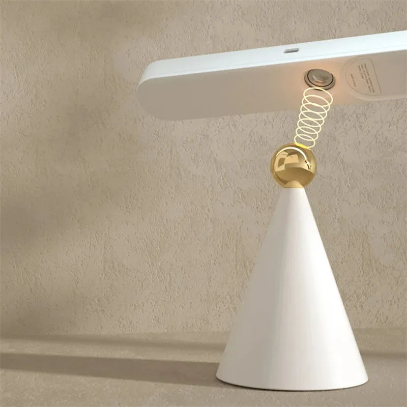 Geometric design table lamp with magnetic base on desk next to USB cable