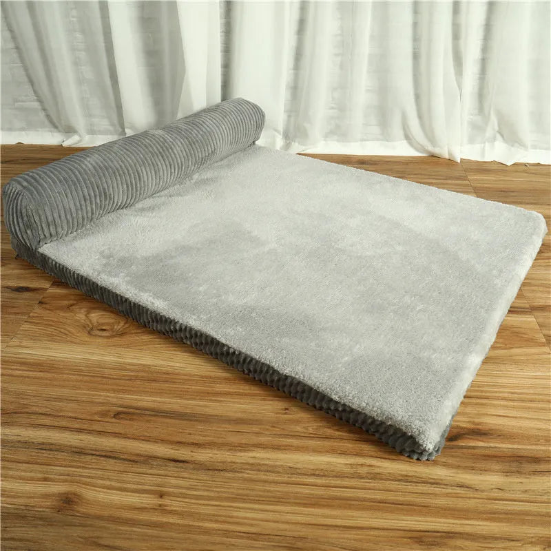 Grey corduroy dog sofa bed with raised sides and a non-slip base on a wooden floor.