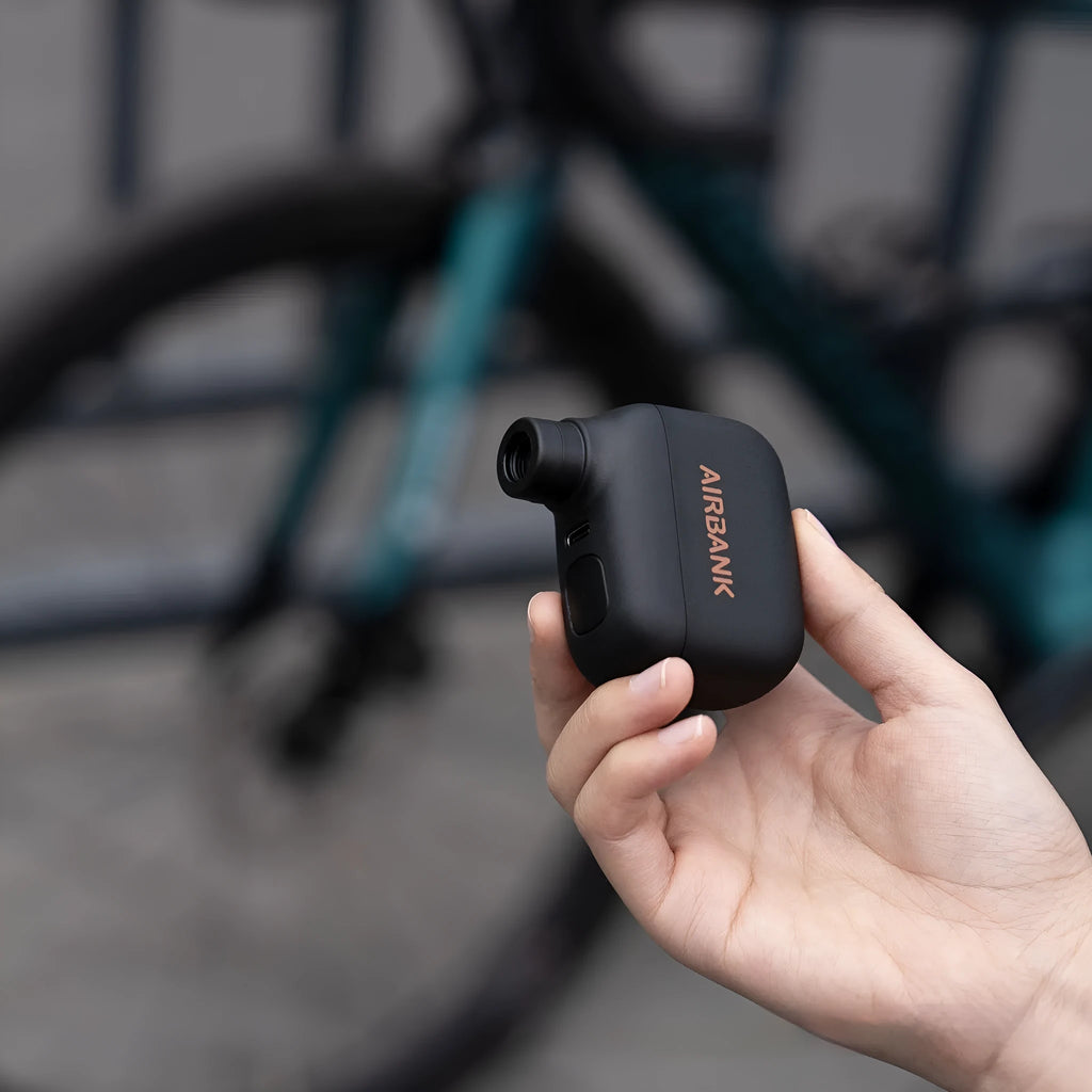 Black AS100 mini electric bicycle pump with USB cable and waterproof storage bag.