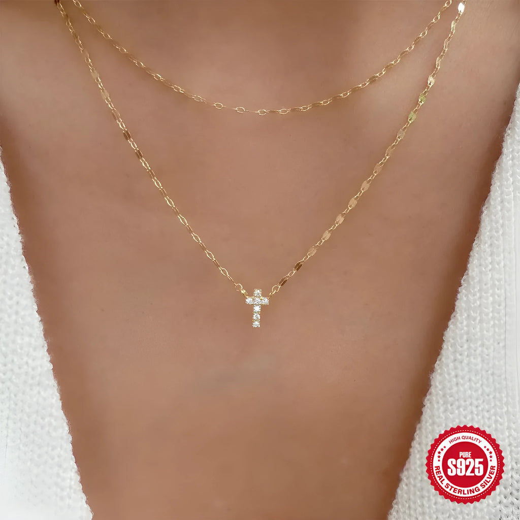 Close-up of a double-layer sterling silver cross pendant on a clavicle chain, available in gold and white gold finishes.
