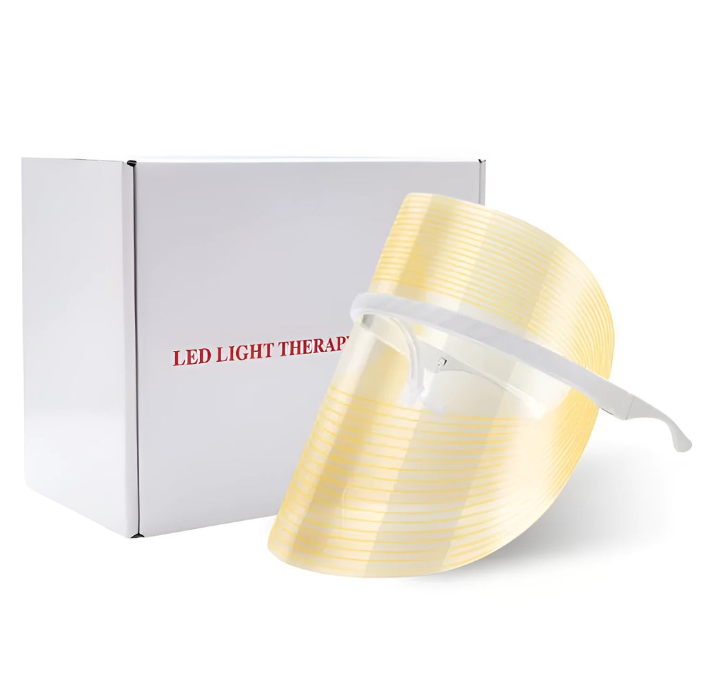 Transparent ABS LED light therapy face mask with red blue yellow lights and USB cable on a flat surface