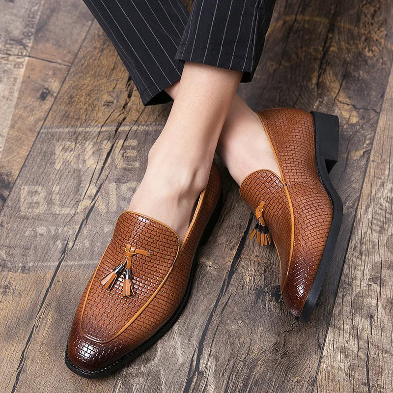 Men's black pointed toe slip-on shoes with a tassel detail on the front.