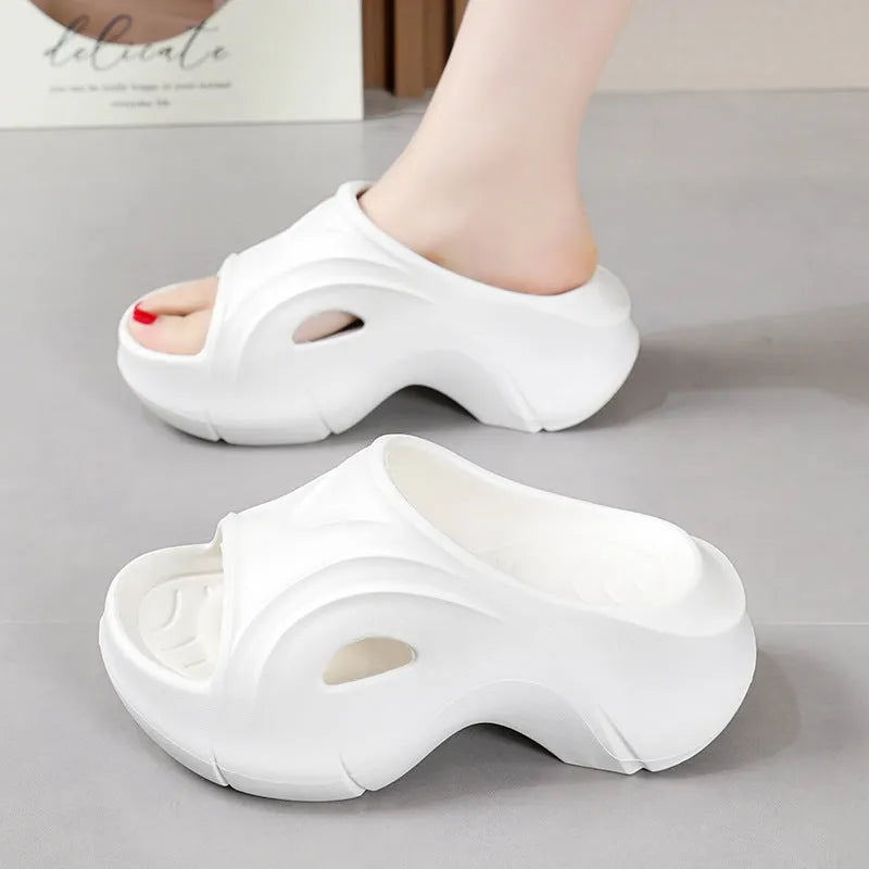 Women's white thick-soled EVA beach slippers with round toe, shown on a sandy background.