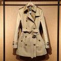 Khaki coloured women's double-breasted trench coat with flight sleeves on a hanger.