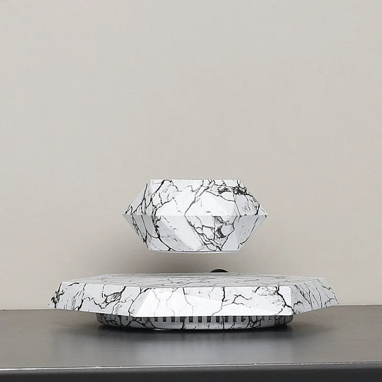 Small marble-colour magnetic levitating plant pot rotating above its base