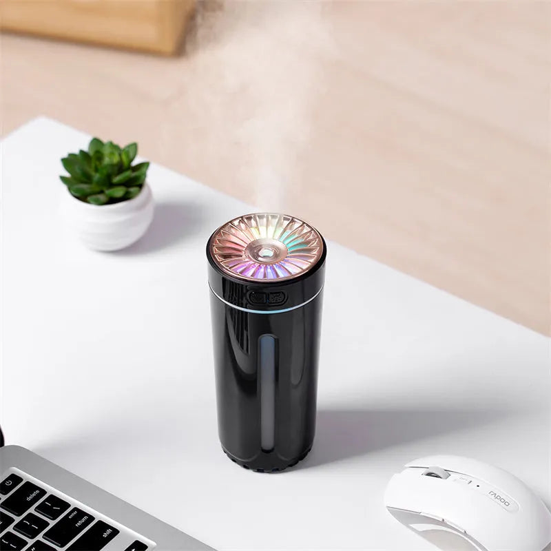 Black portable wireless ultrasonic humidifier with colourful LED lights on a car cup holder.
