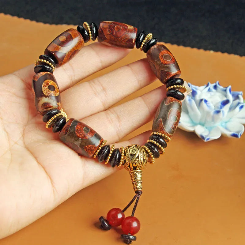 Distressed agate Tibet bead bracelet with three-eye motifs and multiple traditional bead styles on wrist