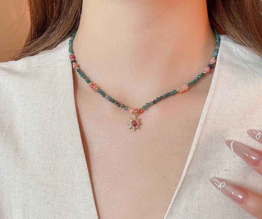 French royal style sun necklace with stone pendant and freshwater pearls on a gold and blue chain.