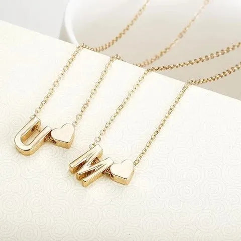 Gold alloy peach heart-shaped pendant with a single letter charm on a silver chain.