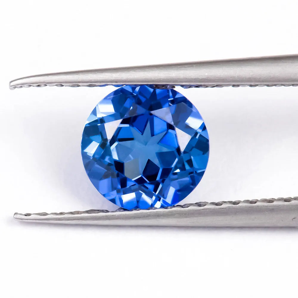 A royal blue loose gemstone with a precision cut, shown against a neutral background.