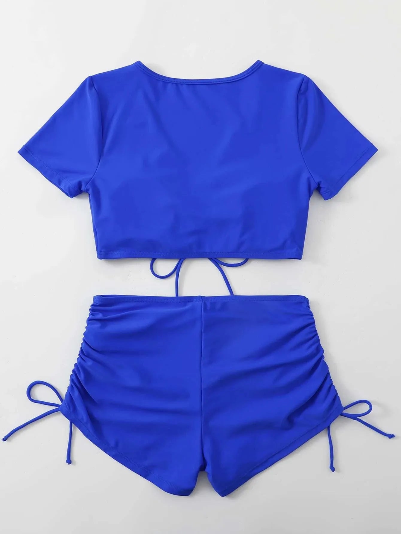 Lady's dark green lace-up front bikini top with matching swim shorts laid flat