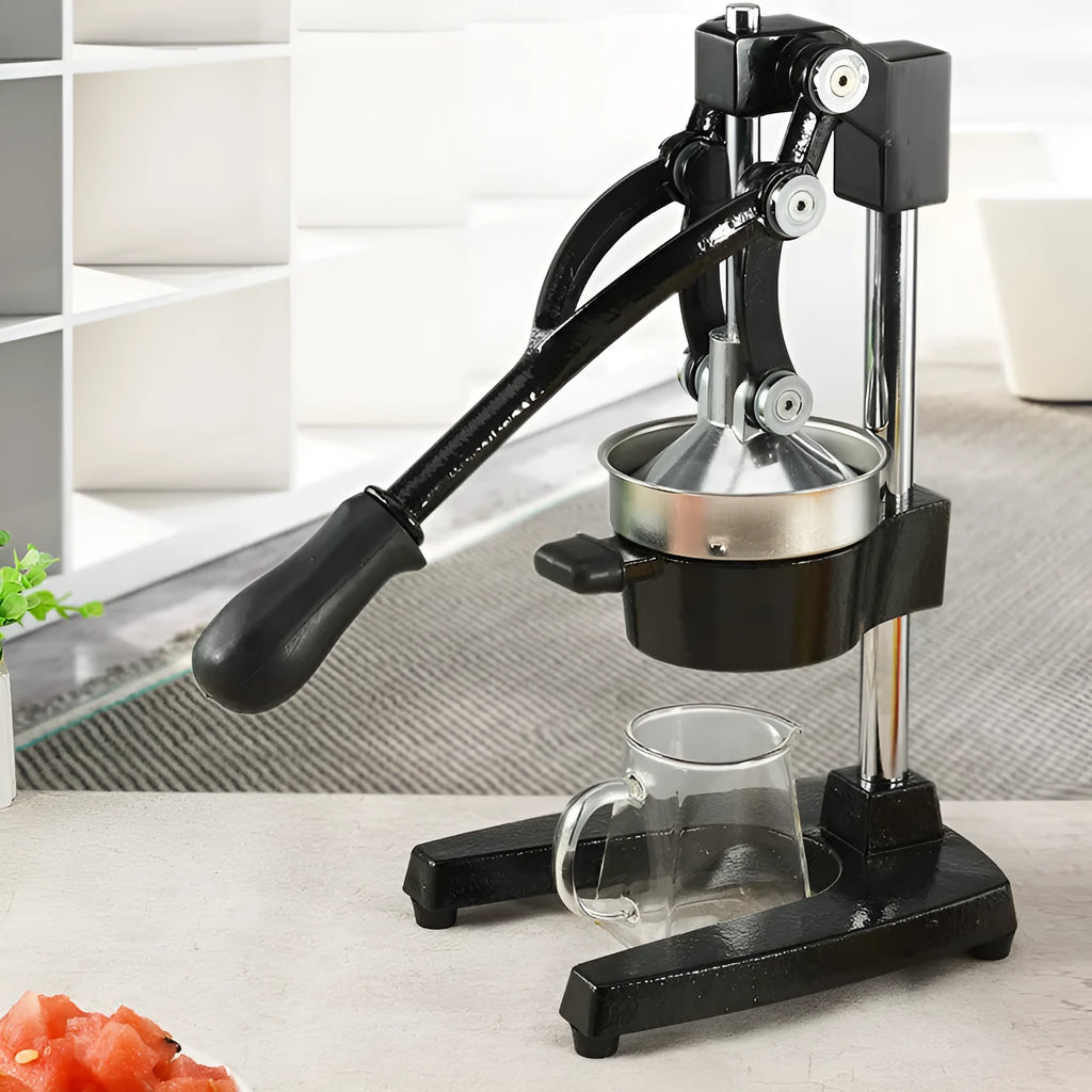 Black or white cast iron manual citrus juicer with stainless steel funnel on a kitchen counter.