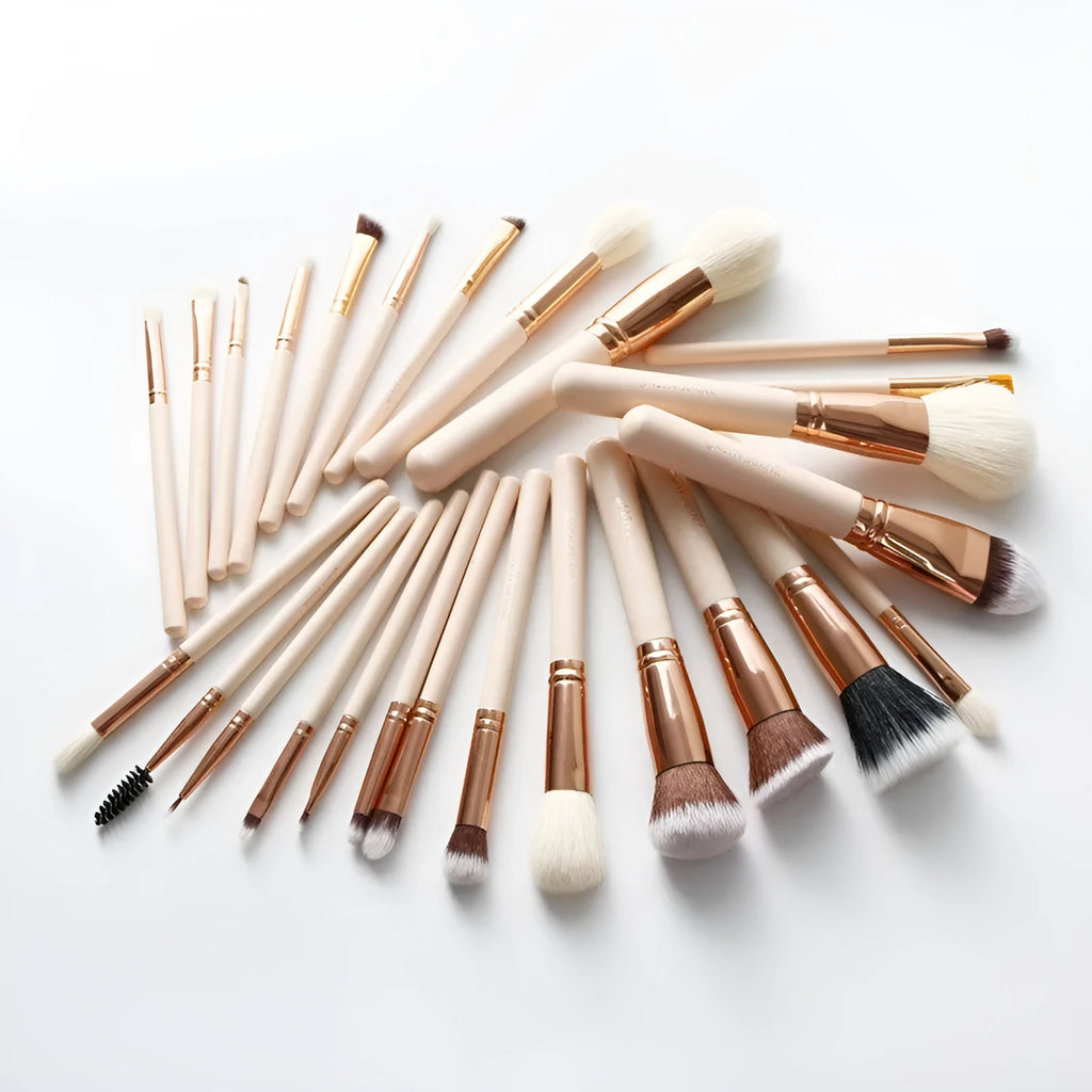 26 pink makeup brushes with wooden handles laid out next to a matching storage bag.