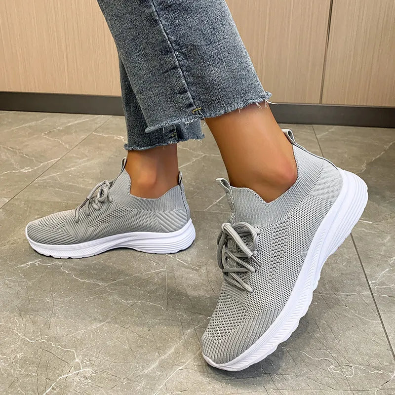 Women's Flyknit mesh running shoes in creamy white colour showing low-top slip-on design and rubber sole.
