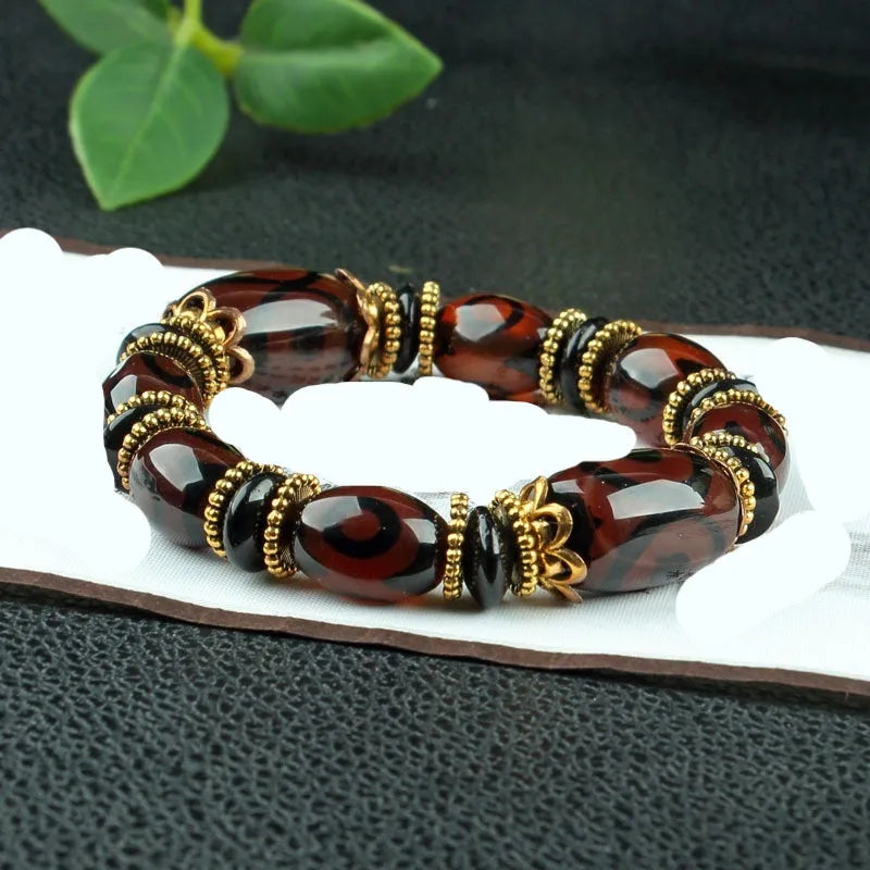 Distressed agate Tibet bead bracelet with three-eye motifs and multiple traditional bead styles on wrist