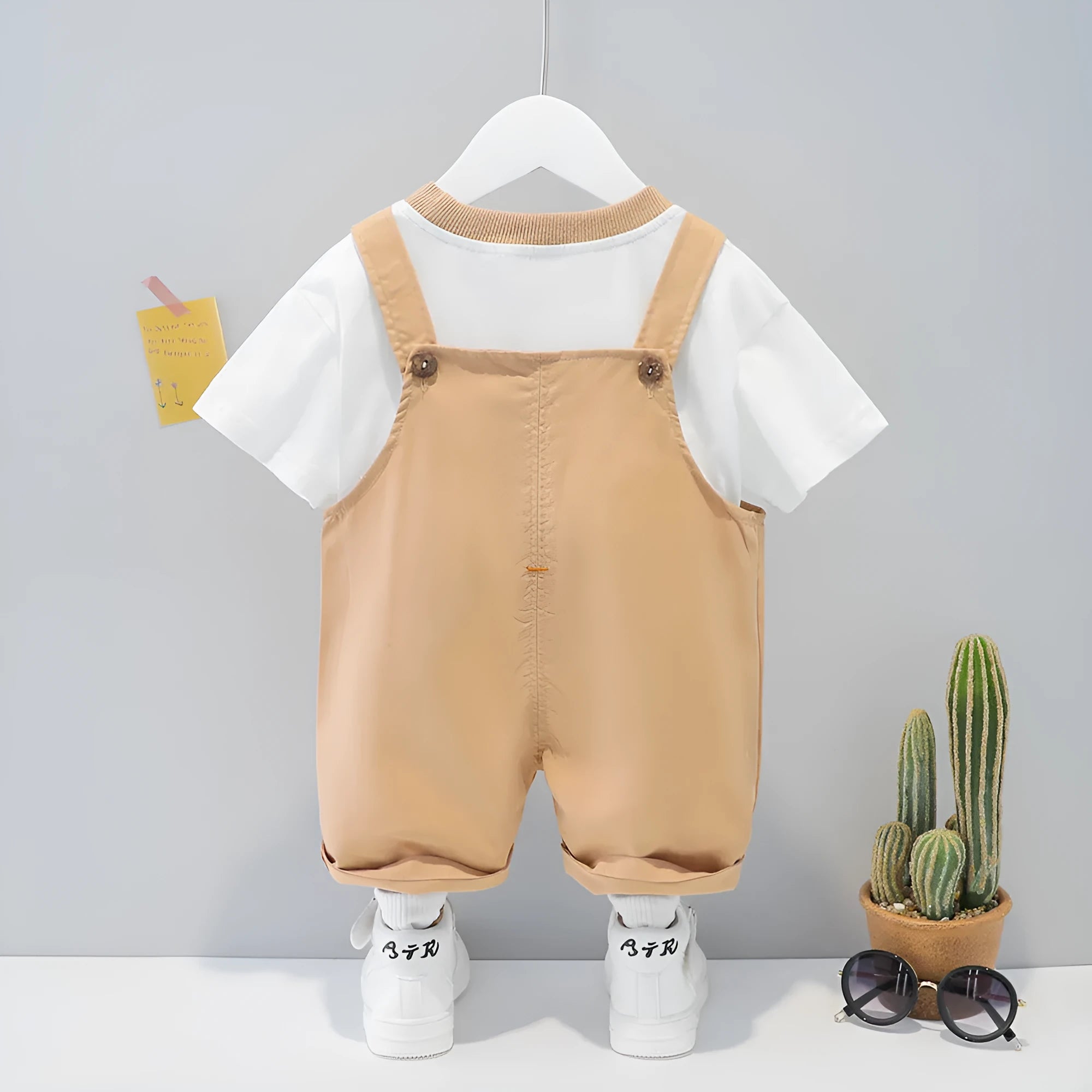 Yellow cotton baby romper suit with cartoon print and openable straps, shown on size 80cm hanger.