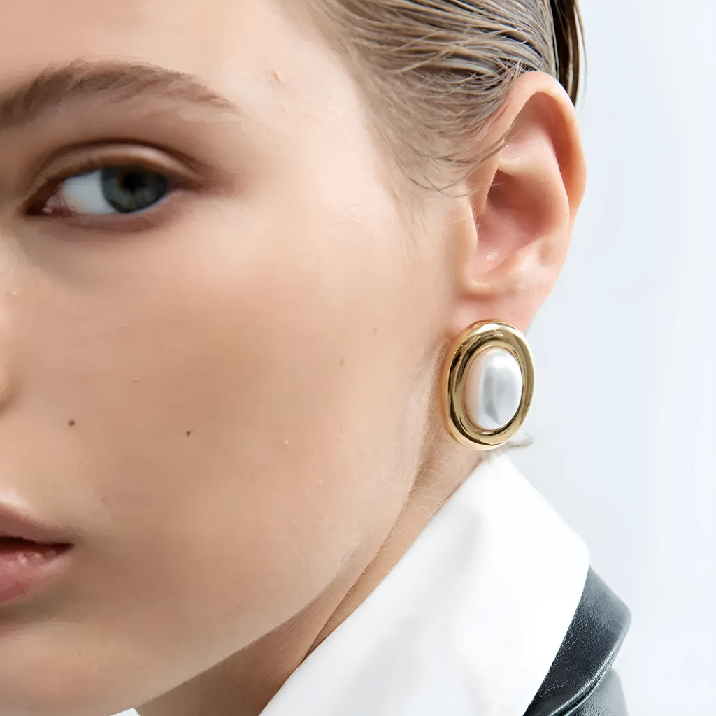A pair of stainless steel post ear studs with small vintage-style pearl accents on a silver-tone background.