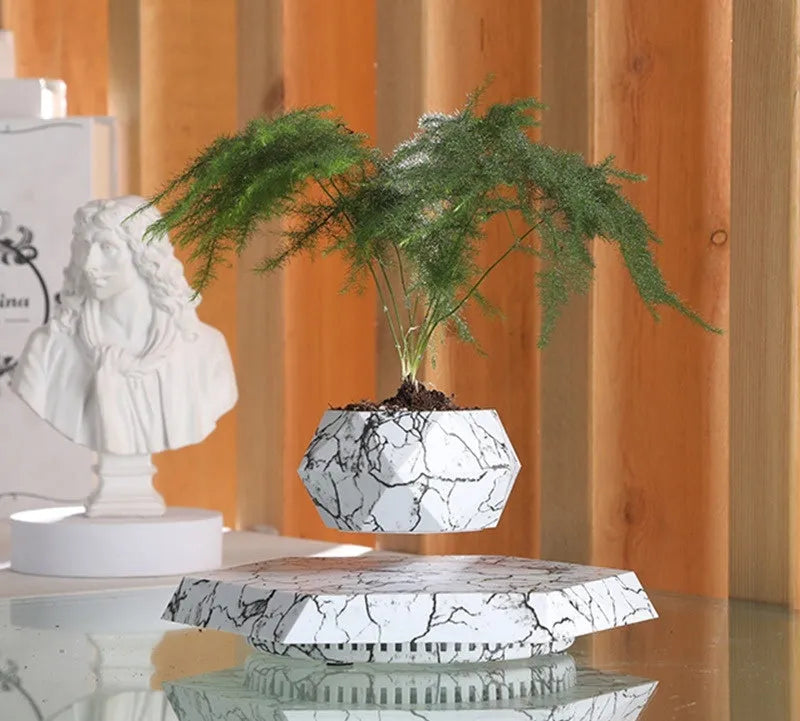 Small marble-colour magnetic levitating plant pot rotating above its base