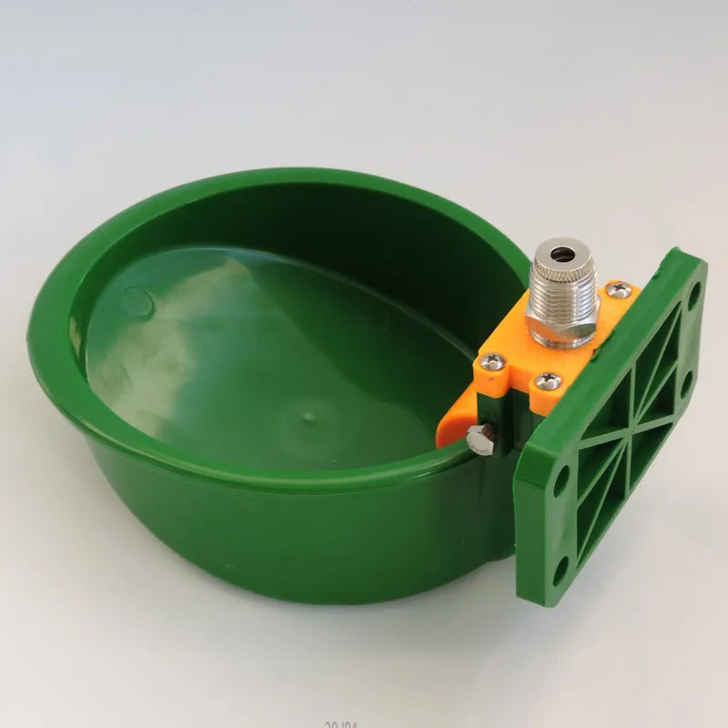 Green plastic automatic drinking bowl with nozzle for sheep and pigs on a farm.