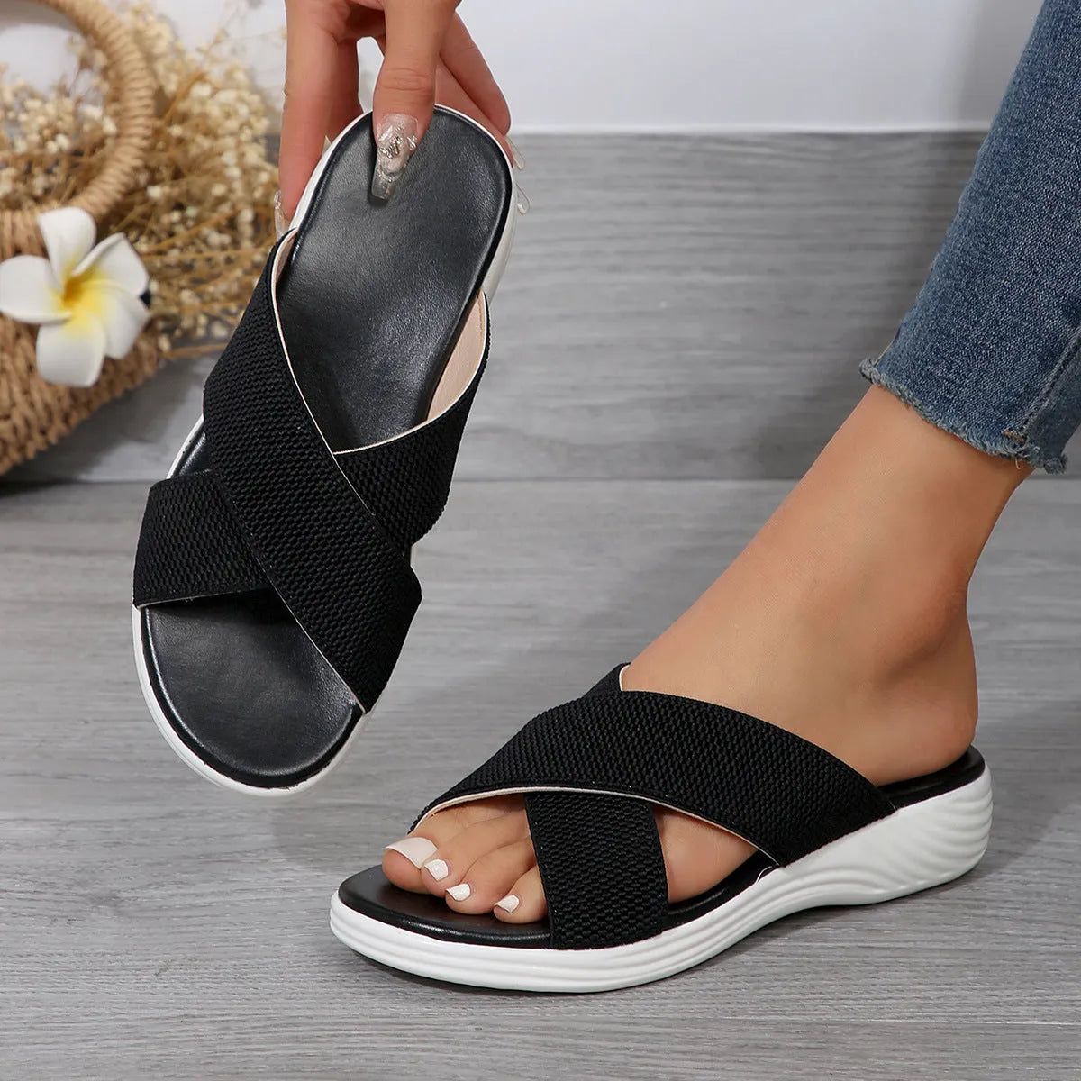 Women's black wedge slippers with a cross strap and peep-toe open front on a thick rubber sole.