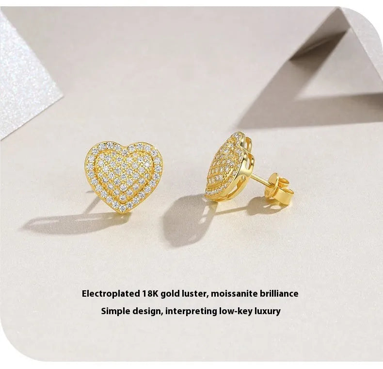 A pair of gold-coloured S925 sterling silver heart stud earrings with moissanite stones.