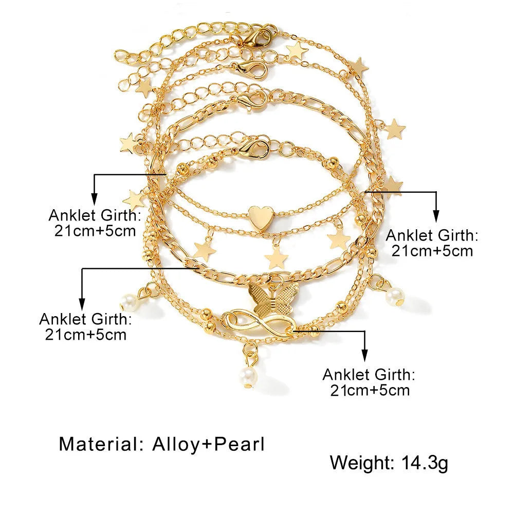 Four alloy anklets with butterfly, pearl and heart charms arranged as a layered jewellery set
