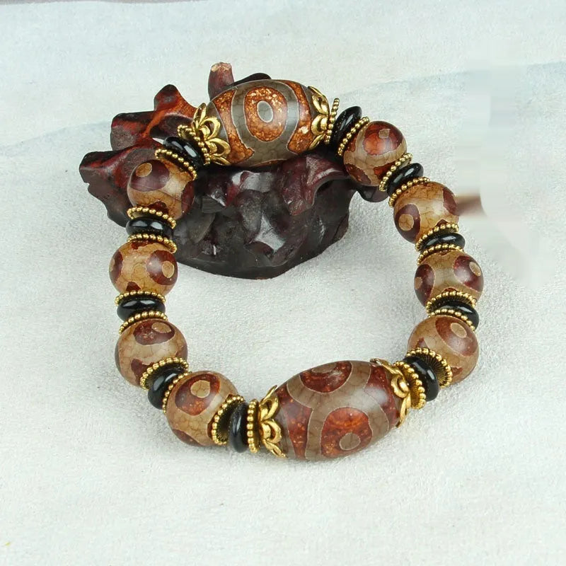 Distressed agate Tibet bead bracelet with three-eye motifs and multiple traditional bead styles on wrist