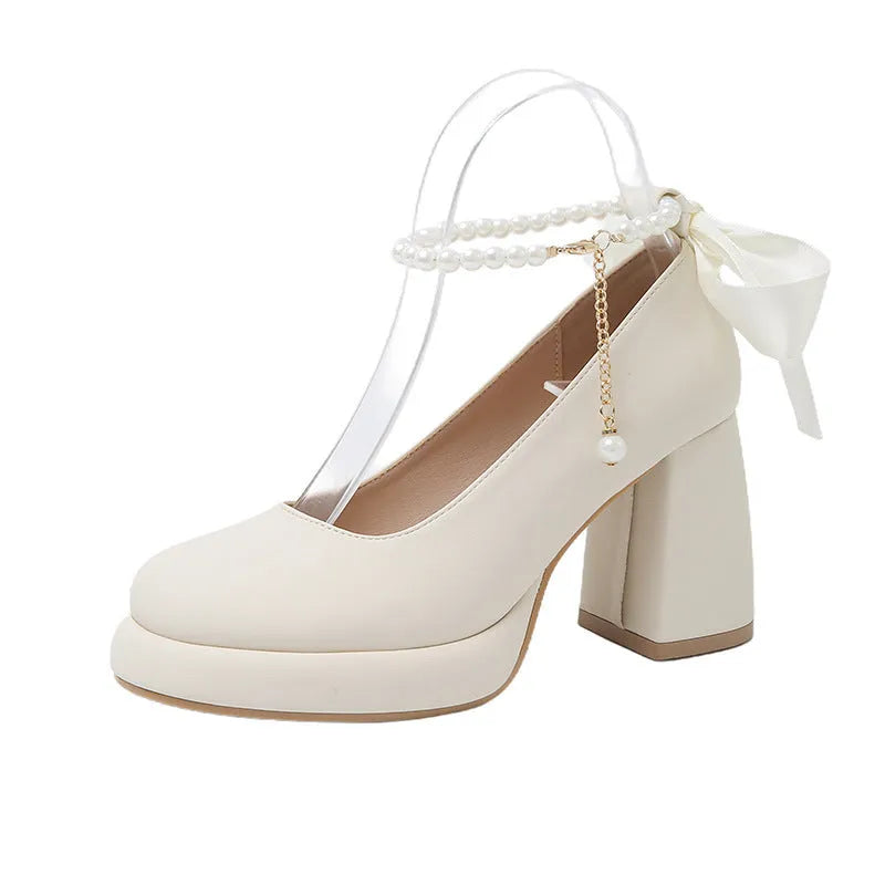 Women's beige Mary Jane shoes with chunky heel and ankle strap buckle on a wooden floor.