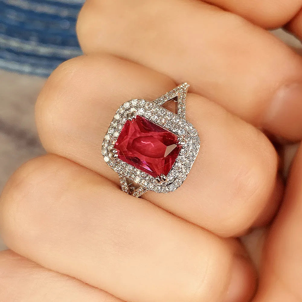Geometric square copper women's ring with a red rhinestone, shown on a finger.