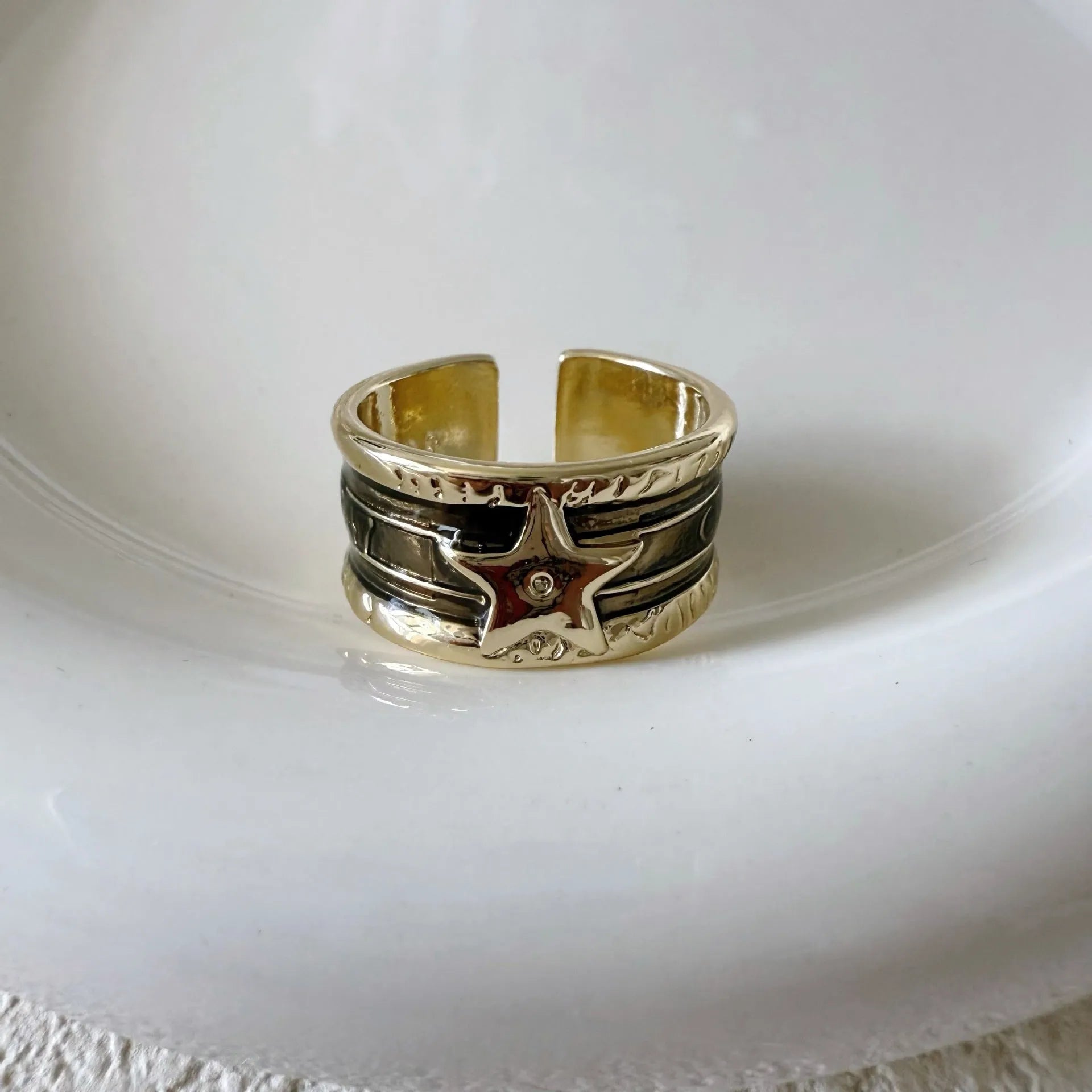 Adjustable geometric drop oil ring in distressed electroplated copper on a hand.