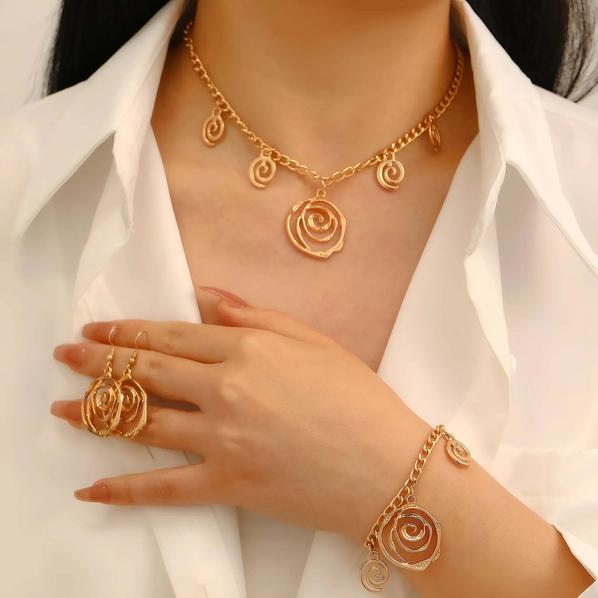 Geometric spiral donut jewellery set with gold necklace, bracelet, and ear hooks on dark background