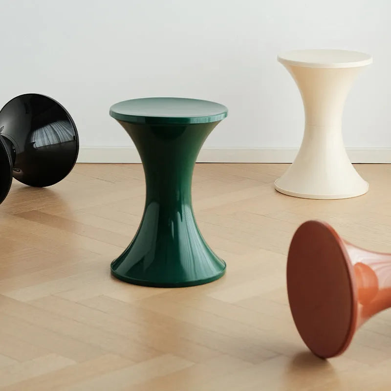 Green plastic hourglass style shoe changing stool on a wooden floor